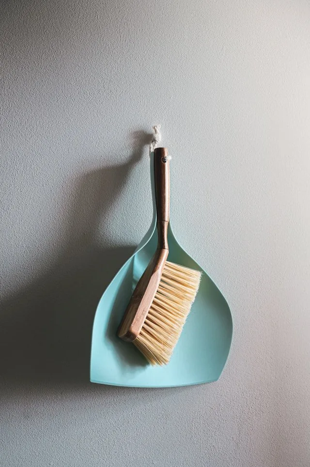 A dustpan and brush hanging on a wall