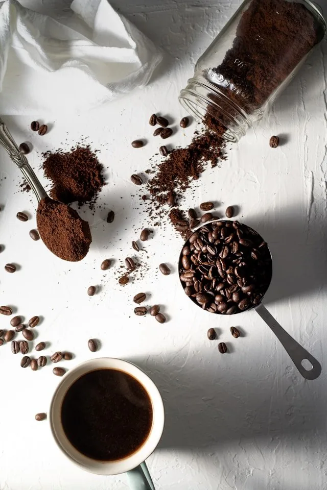Coffee beans spilling from a jar beside a cup of coffee